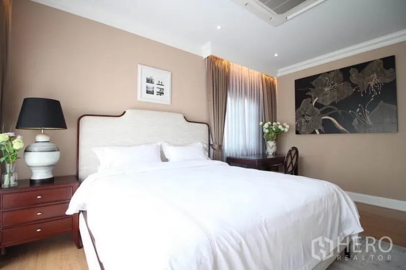 Detached House for rent or sale in Lat Phrao, Bangkok - Master bedroom view showing bedside tables, artwork and soft drapes.