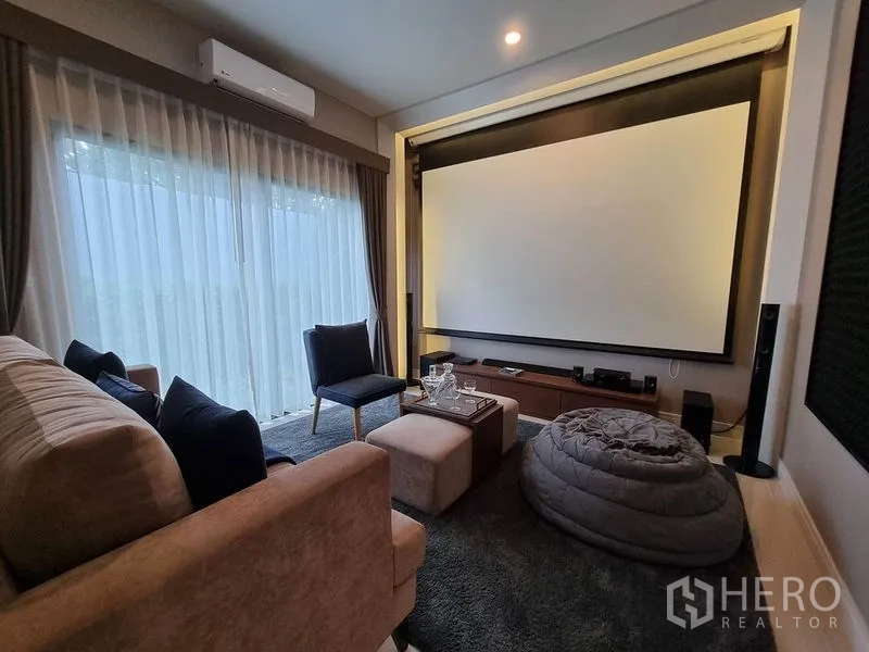 Detached House for rent in Prawet, Bangkok - Cozy home theater with large projector screen, plush seating and floor‑to‑ceiling curtains.
