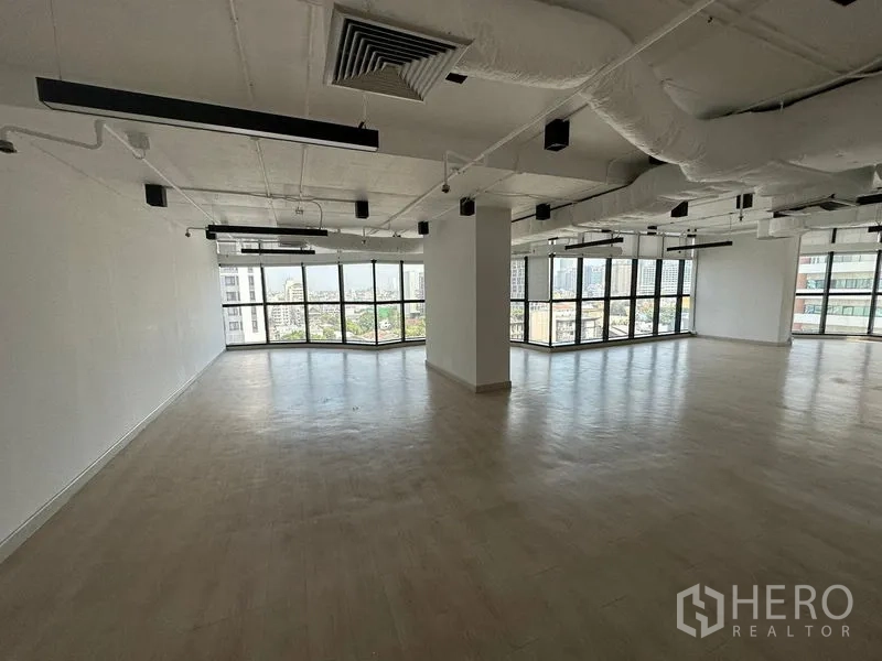 Office Space for rent - Corner workspace featuring floor‑to‑ceiling windows and modern industrial lighting.