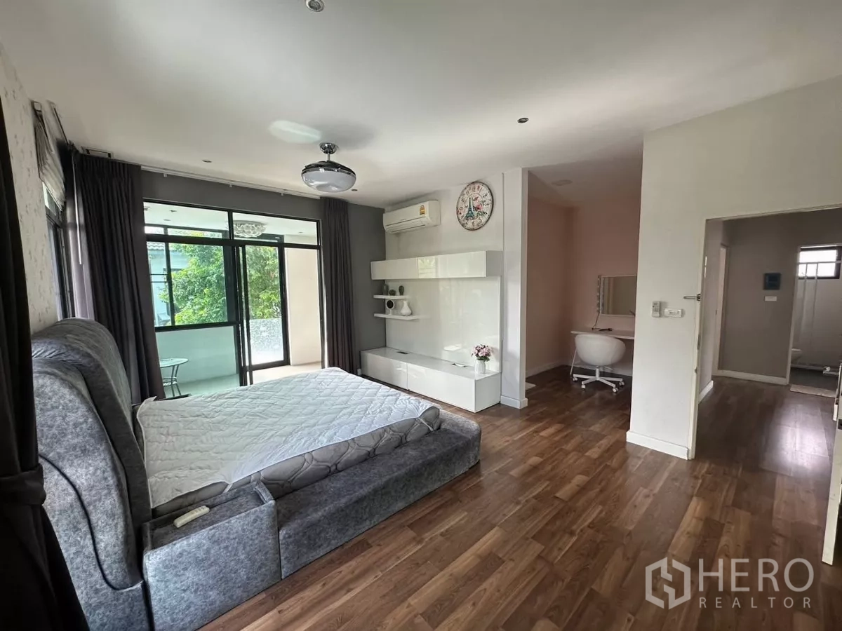Detached House for rent or sale in Bang Kapi, Bangkok - Spacious master bedroom with wood floors, built-in cabinet and access to a balcony.
