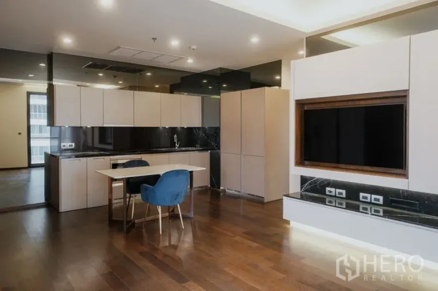 Condominium for rent or sale in Watthana, Bangkok - Open‑plan living with modern kitchen, marble dining table and TV console.