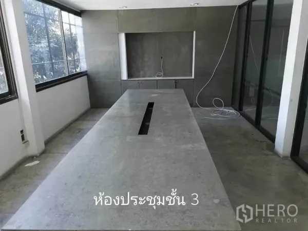 Home Office for rent in Khlong Toei, Bangkok - Bright meeting room with a long table, large windows, and built-in cabinets.