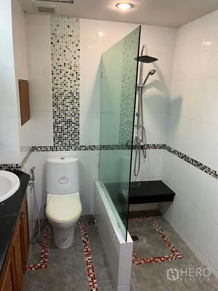 Townhouse for sale in Phra Khanong, Bangkok - Modern bathroom with glass shower screen, mosaic accents, vanity, and toilet.