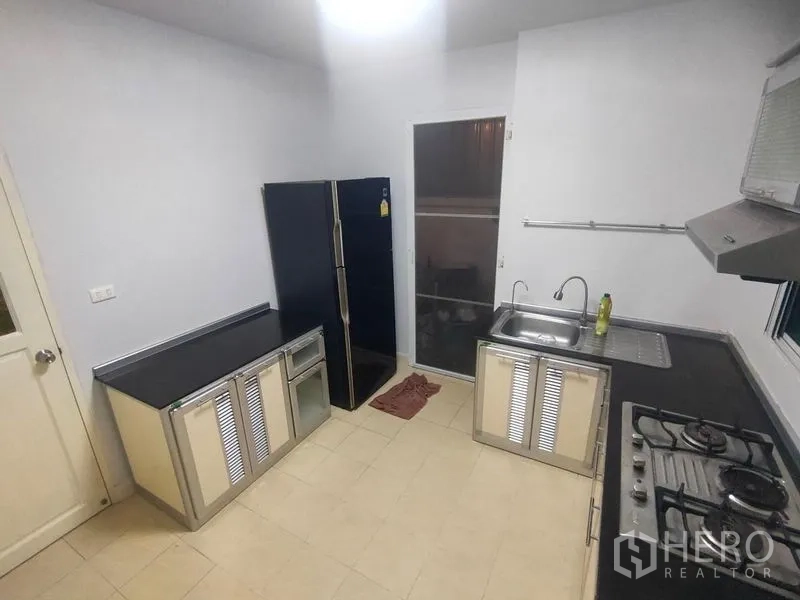 Detached House for rent in Prawet, Bangkok - Kitchen second angle showing sink, double-door fridge and ample worktops.