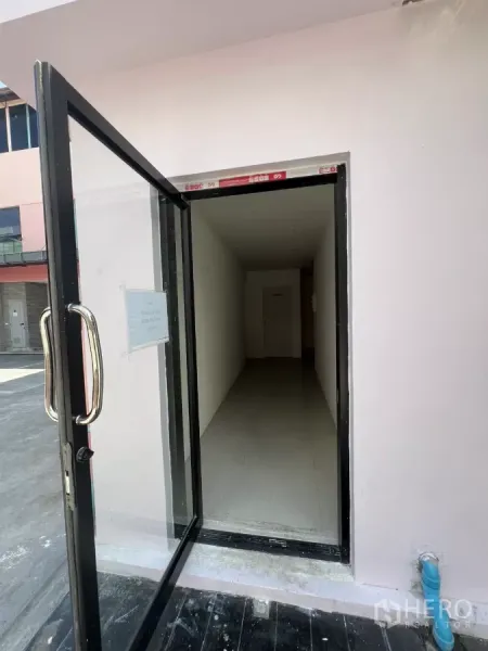 Retail Space for rent - Glass door entrance opening to a narrow white hallway.