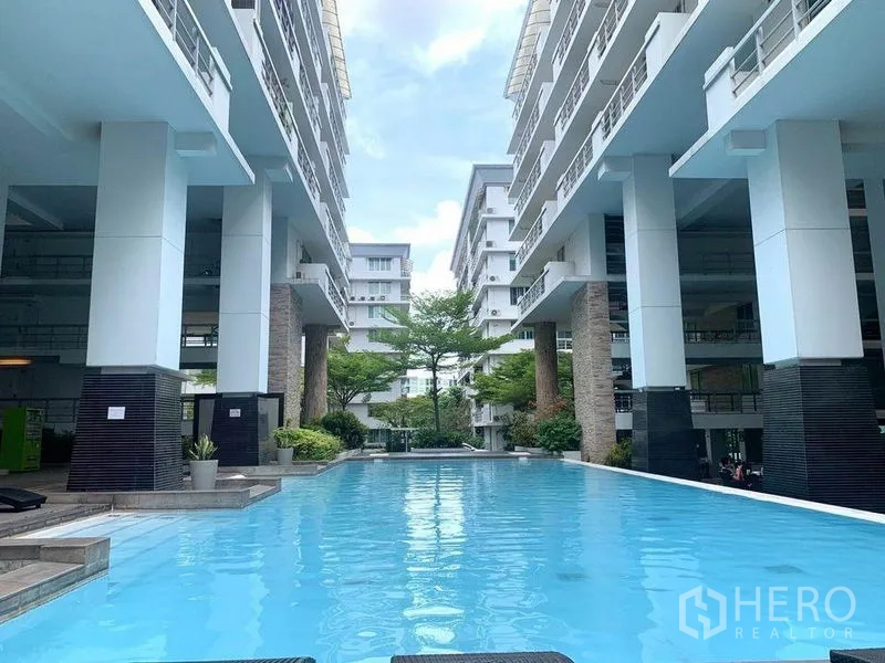 Condominium for rent in Khlong Toei, Bangkok - Long outdoor swimming pool set between modern low‑rise condo buildings.