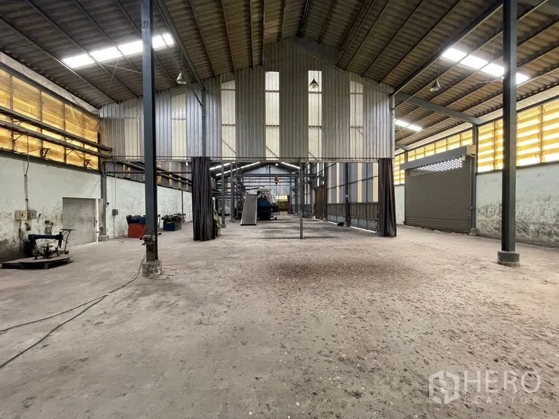 Warehouse for rent or sale in Bang Bon, Bangkok - Long-span warehouse aisle with a suspended structure and machinery lines.