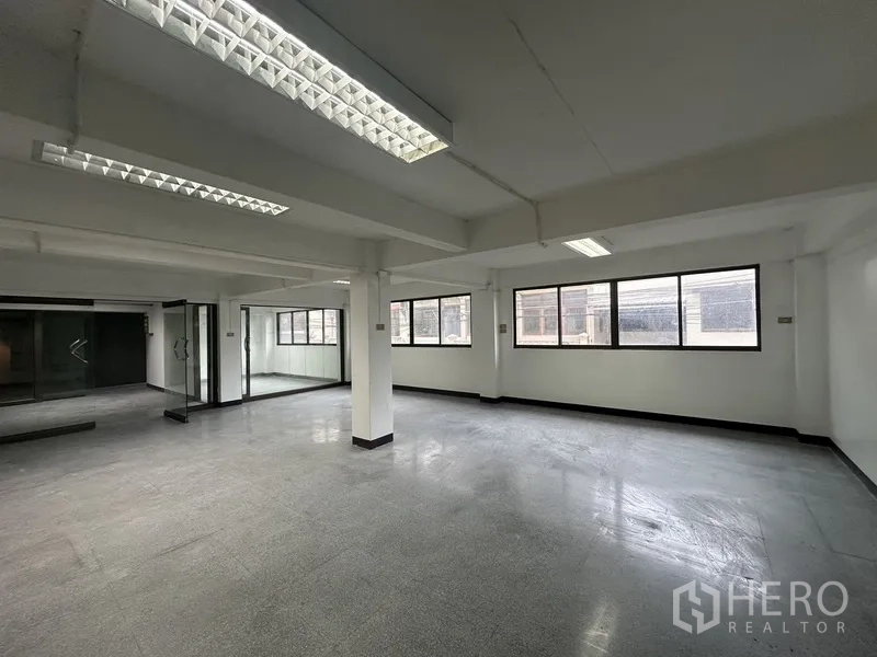Office Space for rent in Khlong Toei, Bangkok - Bright corner workspace with multiple windows, glass partitions and grey flooring.
