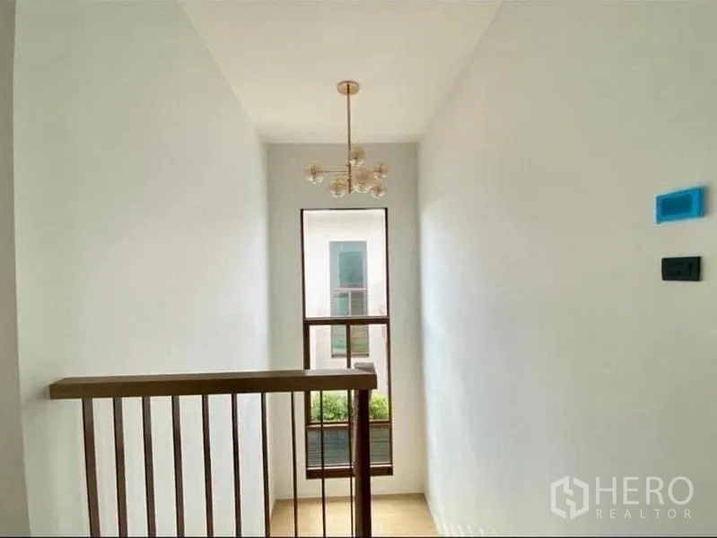 Detached House for sale in Bang Kapi, Bangkok - Staircase landing with pendant chandelier and tall window bringing in natural light.
