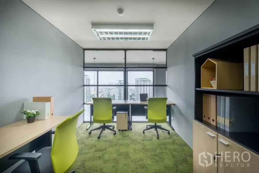 Office Space for rent in Chatuchak, Bangkok - Private office with green carpet, desks, shelving, and a city skyline view through a glass partition.