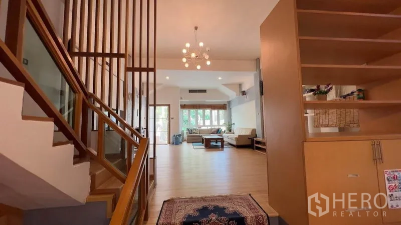 Townhouse for rent or sale in Khlong Toei, Bangkok - Entrance hall with wooden staircase and chandelier leading to an open-plan lounge.