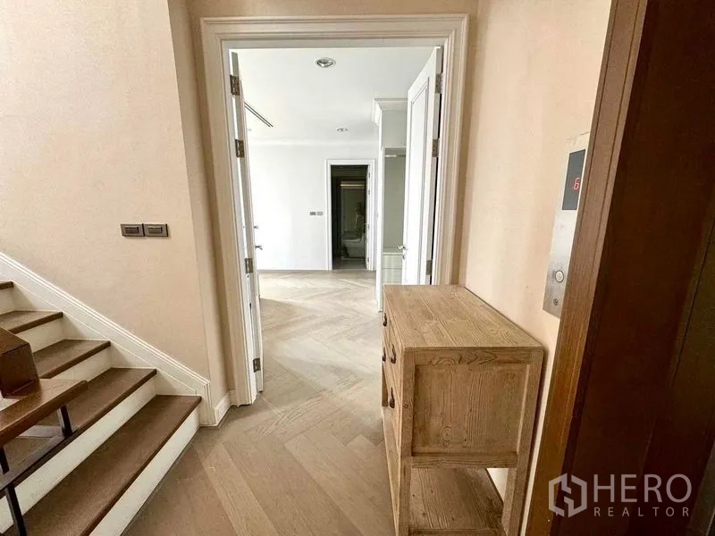 Townhouse for rent in Watthana, Bangkok - Bright landing with staircase, herringbone floors and a doorway to rooms beside a private lift panel.
