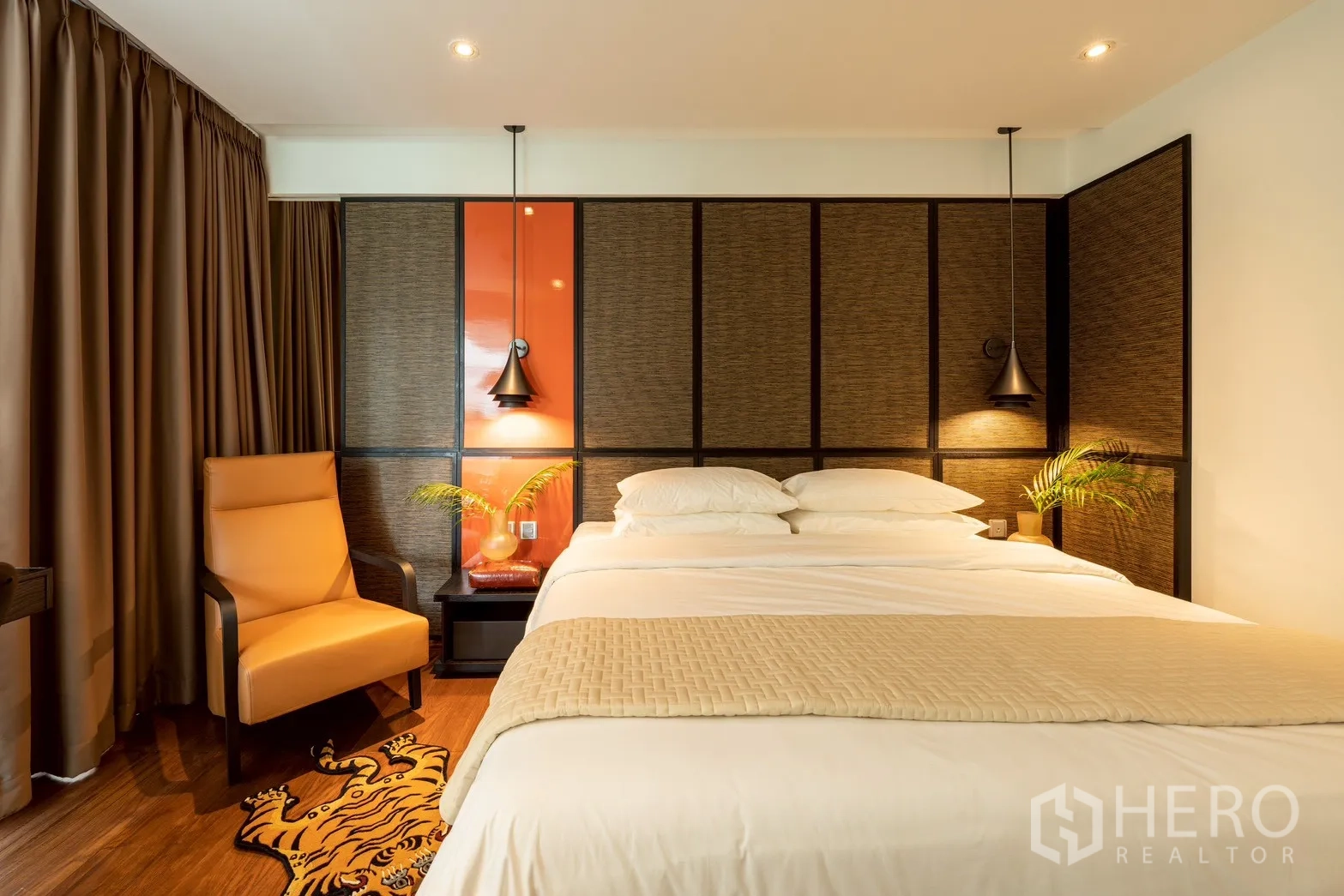Condominium for rent or sale in Pathum Wan, Bangkok - Bedroom with king bed, accent wall panels, pendant lights, and a lounge chair.