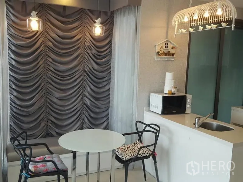 Condominium for rent in Khlong Toei, Bangkok - Compact dining nook with round table, pendant lights and kitchenette counter.