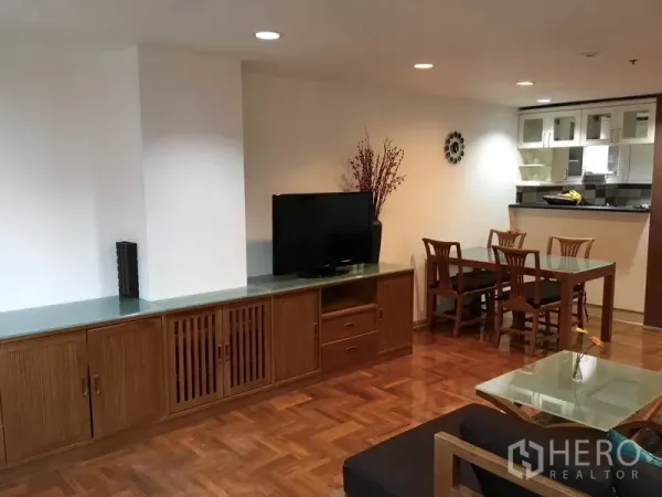 Condominium for rent in Pathum Wan, Bangkok - Living area with built-in TV console, four-seat dining table, and pass-through to the kitchen.
