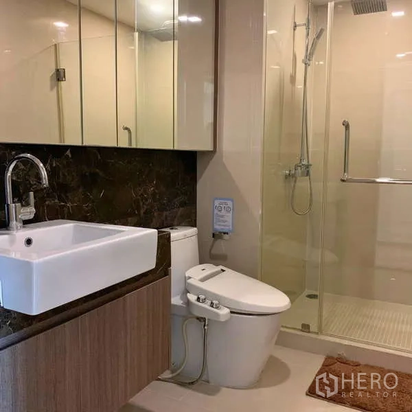 Condominium for rent - Second bathroom with glass-enclosed shower, bidet toilet, and vanity.