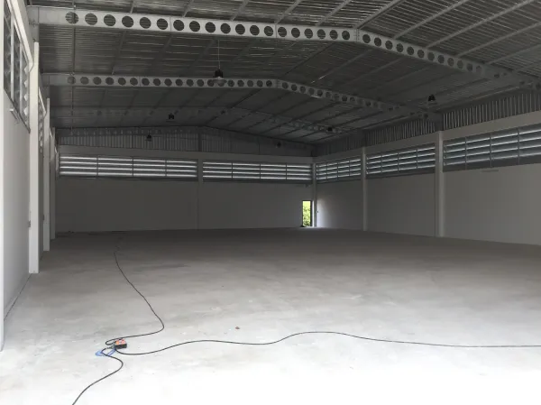 Factory for sale in Lam Luk Ka, Pathum Thani - Spacious high-ceiling warehouse with steel trusses, louvered vents and concrete floor.