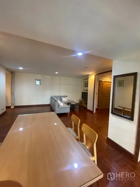 Condominium for rent in Pathum Wan, Bangkok - Open-plan living and dining space on wood flooring leading toward the entrance door.