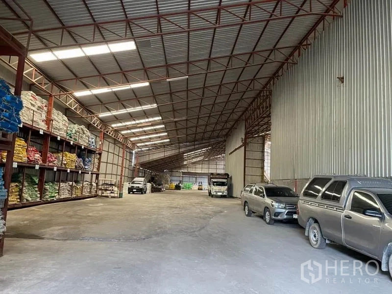 Warehouse for sale in Lam Luk Ka, Pathum Thani - Wide storage aisle with pallet racking, skylights, and space for trucks inside the warehouse.