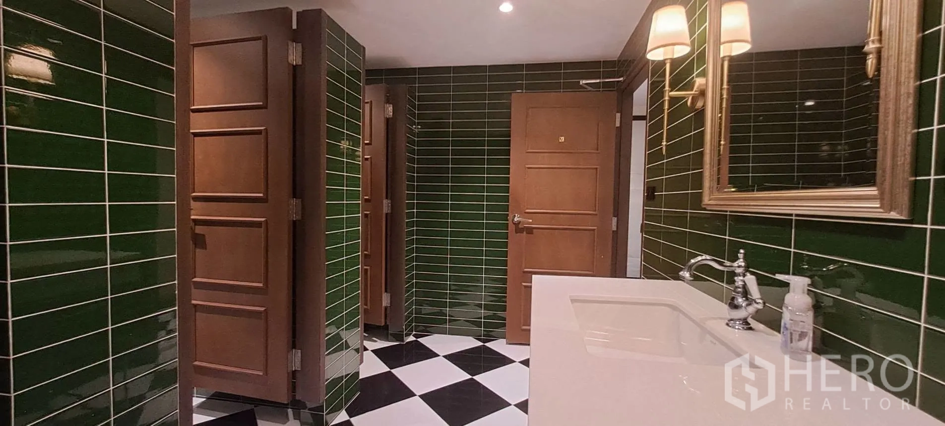 Home Office for rent in Lat Phrao, Bangkok - Restroom finished in dark green tiles with vanity and mirrors.
