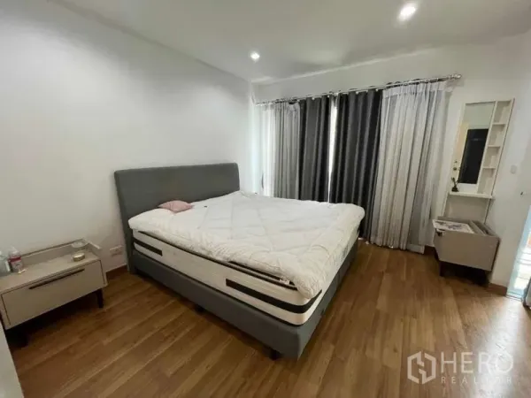Townhouse for rent in Suan Luang, Bangkok - Master bedroom with king bed, bedside tables and floor-to-ceiling curtains.
