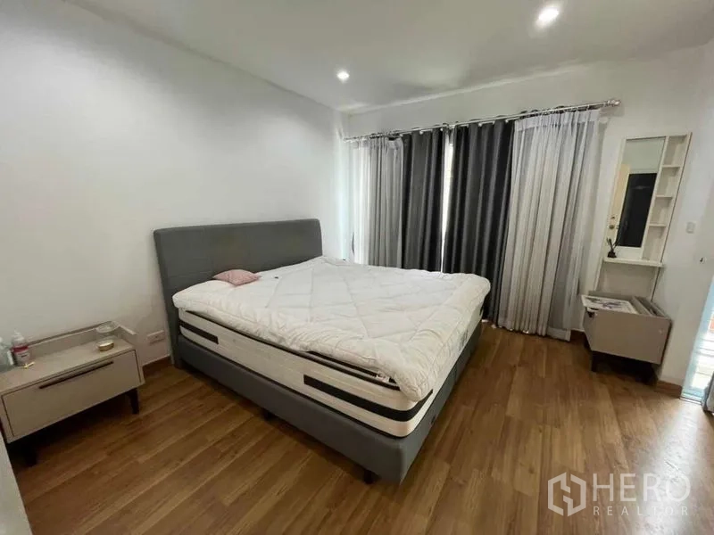 Townhouse for rent in Suan Luang, Bangkok - Master bedroom with king bed, bedside tables and floor-to-ceiling curtains.