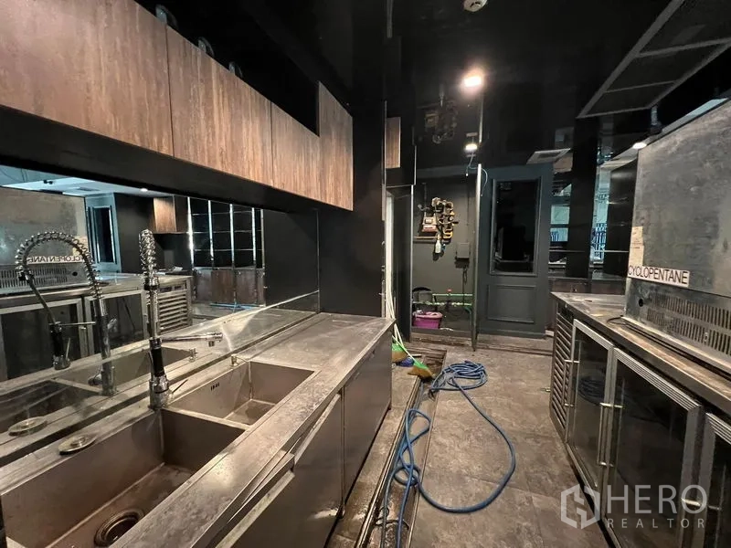 零售空间 出租 - 后场商用区，配不锈钢水槽、操作台与冷藏柜。