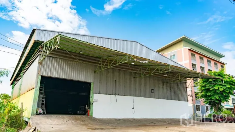 Warehouse for rent in Thanyaburi, Pathum Thani - Front exterior of a metal-clad warehouse in Thanyaburi, Pathum Thani with a wide covered loading dock and ramp.