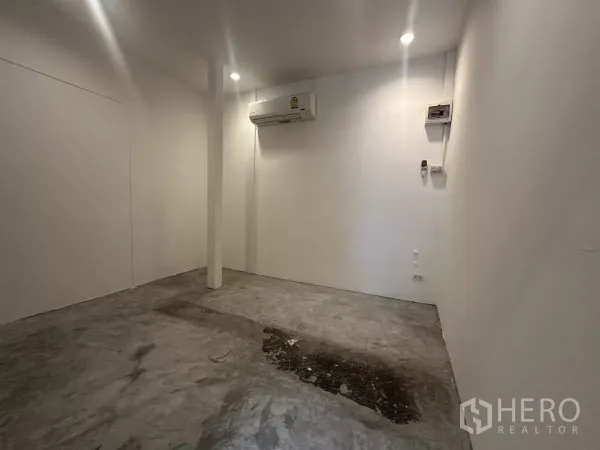 Retail Space for rent - Compact 10 sqm interior with white walls, central pillar, concrete flooring, ceiling spotlights and wall-mounted air conditioner.