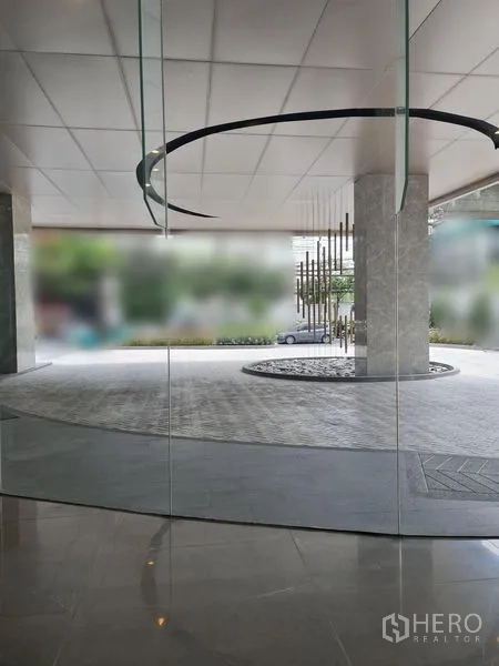 Retail Space for rent - View through glass to the lobby with circular ceiling feature and decorative sculpture outside.