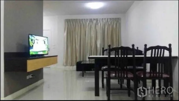 Townhouse for rent in Suan Luang, Bangkok - Open-plan living and dining area with tiled floors, curtains, TV console and dining set.