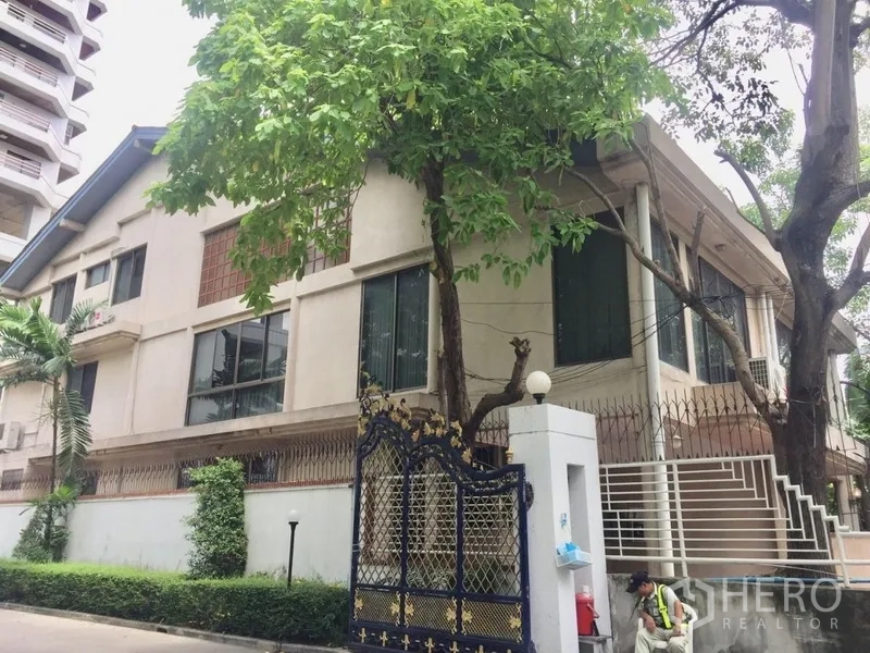 Townhouse for rent in Watthana, Bangkok - Corner view of the townhouse with decorative gate, stair entry and tall trees.