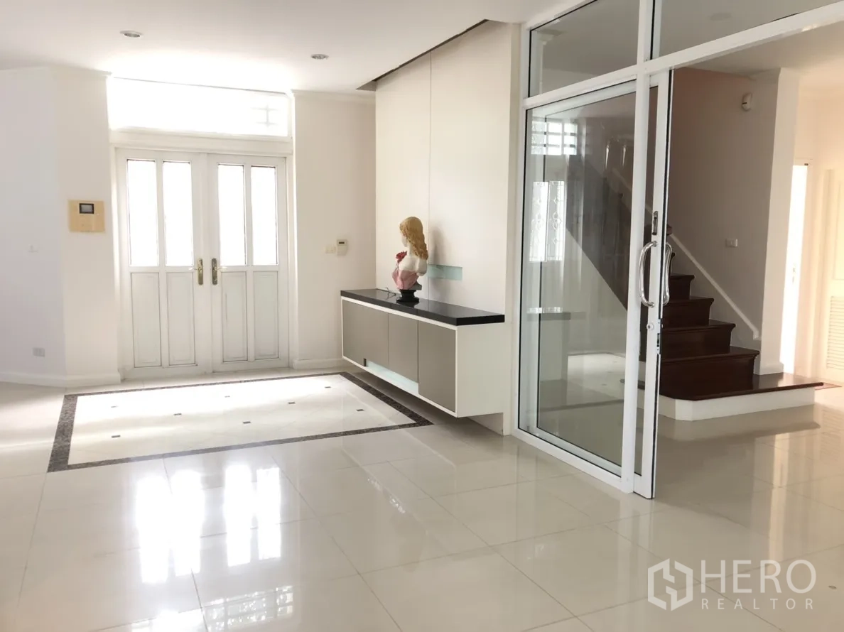 Detached House for rent or sale in Lat Phrao, Bangkok - Spacious foyer with double doors, glass sliding partition and a wooden staircase.