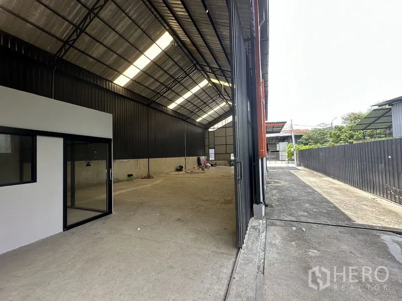 Warehouse for rent in Lat Phrao, Bangkok - Wide warehouse opening to the yard with high ceiling and ventilation louvers.