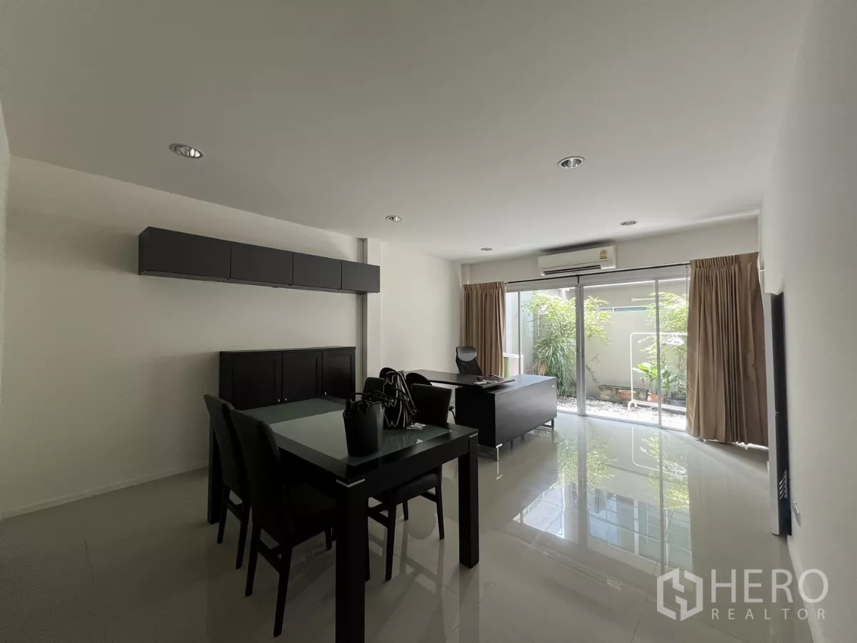 Townhouse for rent in Suan Luang, Bangkok - Dining table and work desk facing sliding doors with views of the courtyard greenery.