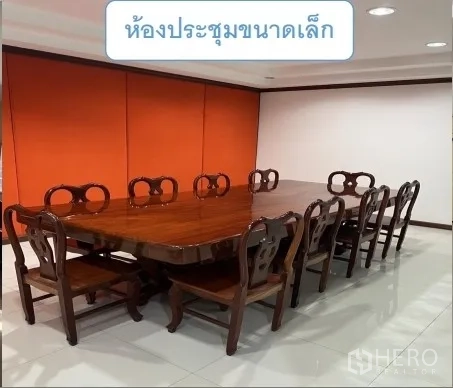Warehouse for rent in Mueang Pathum Thani, Pathum Thani - Small meeting room with a long wooden table and classic chairs against an orange wall.
