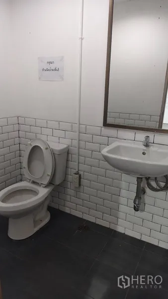 Office Space for rent in Pathum Wan, Bangkok - Restroom with white subway tile walls, toilet, sink and wall mirror.