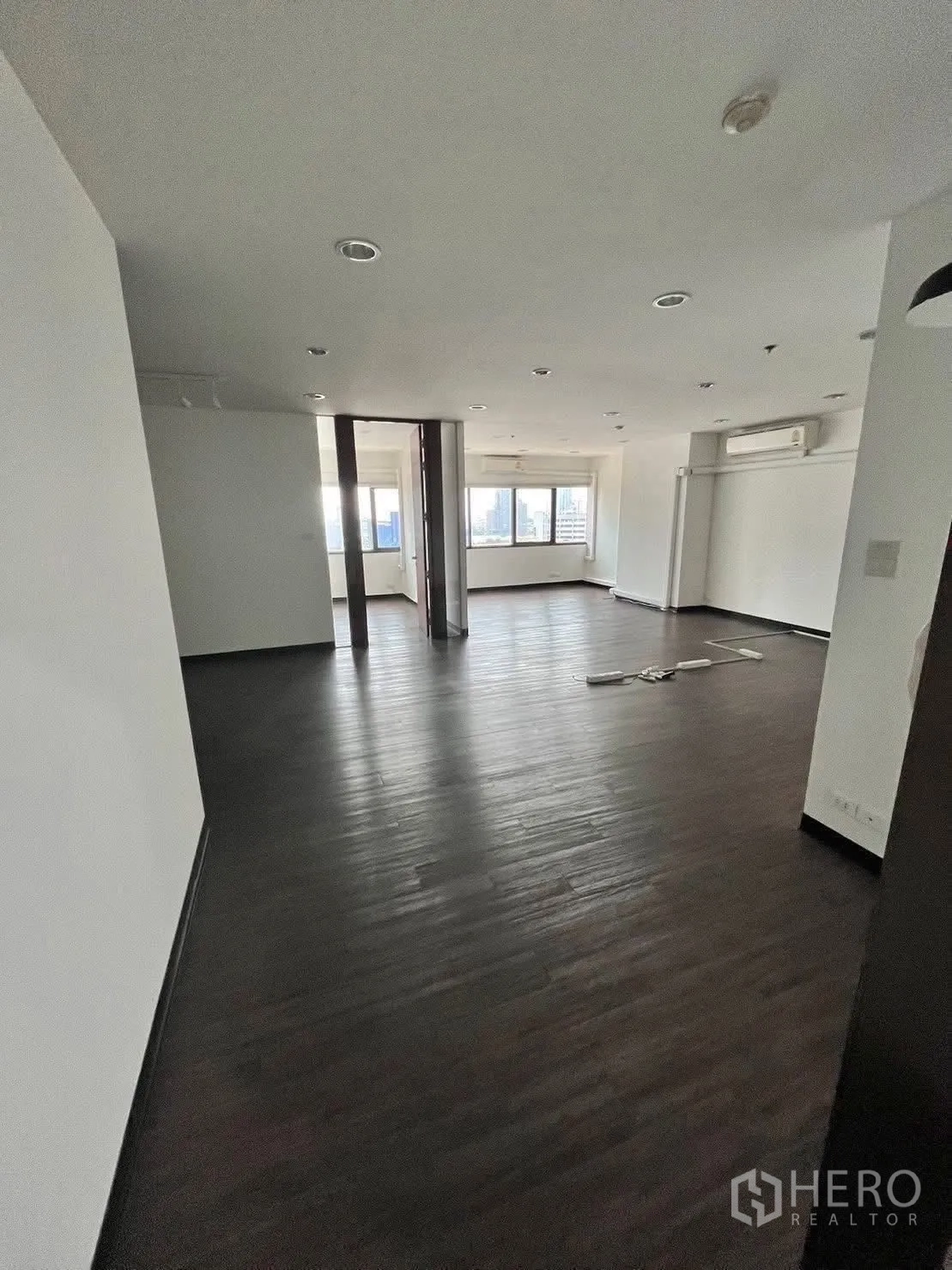 Office Space for rent in Watthana, Bangkok - Spacious office area with ceiling lights, partition panels and city-facing windows.