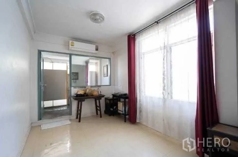 Detached House for rent in Khlong Toei, Bangkok - Light-filled room with large windows, air conditioning, and door to an adjoining bathroom.