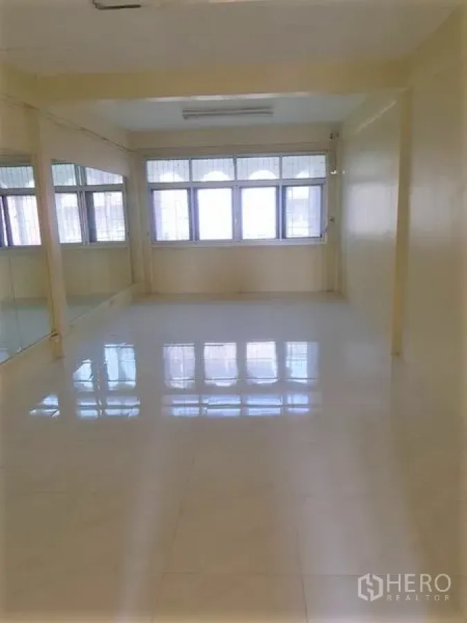 Retail Space for rent in Khlong Toei, Bangkok - Large open‑plan room with white floor tiles, mirrored wall panels and wide windows letting in light.