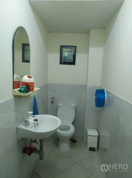 Home Office for rent in Yan Nawa, Bangkok - Compact restroom with toilet, wall mirror and sink, finished in light grey tiles.