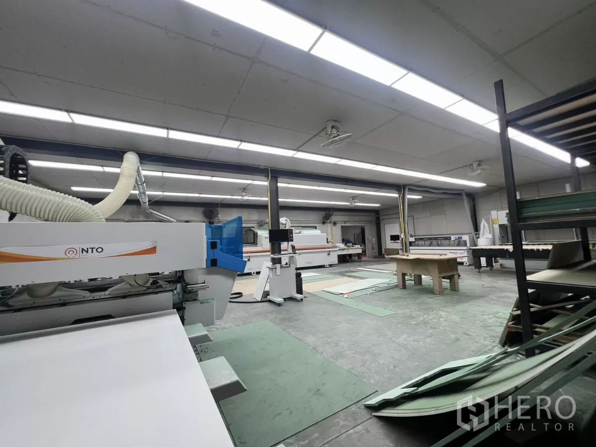 Warehouse for rent or sale in Lat Krabang, Bangkok - Workshop floor with industrial machinery, long fluorescent lighting and worktables.