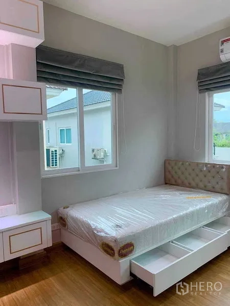 Detached House for rent in Bang Khen, Bangkok - Bedroom with upholstered headboard, under-bed drawers and two windows.