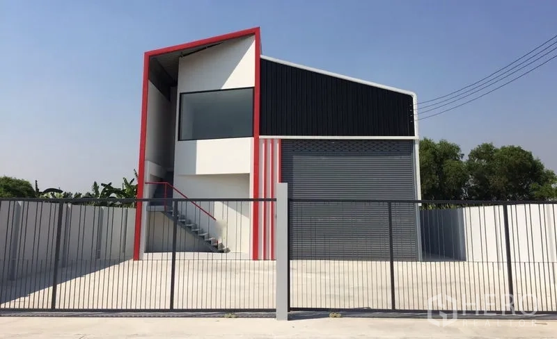 Warehouse for sale in Khlong Luang, Pathum Thani - Front elevation of gated warehouse with large driveway and parking apron.