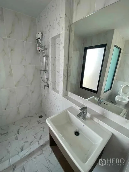 Townhouse for rent in Prawet, Bangkok - Second bathroom finished in marble-look tiles with shower and vanity.