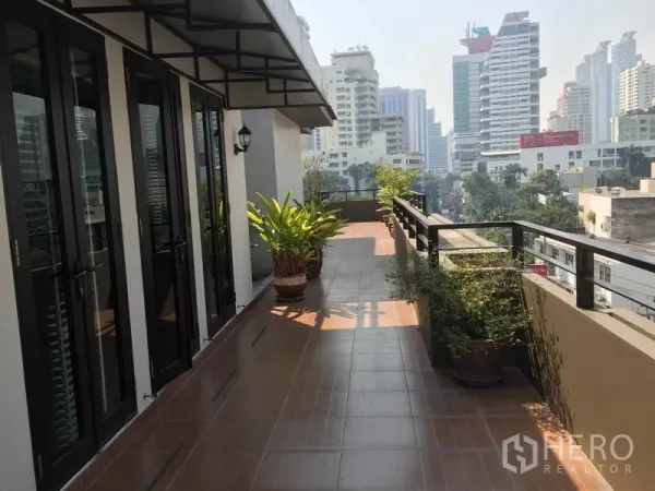 Condominium for rent in Khlong Toei, Bangkok - Expansive private terrace with city skyline views and potted plants.