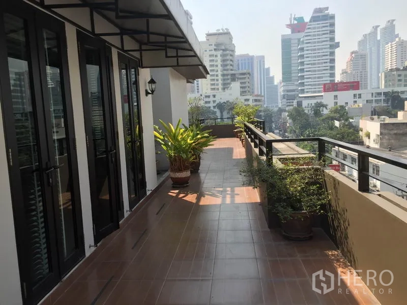 Condominium for rent in Khlong Toei, Bangkok - Expansive private terrace with city skyline views and potted plants.