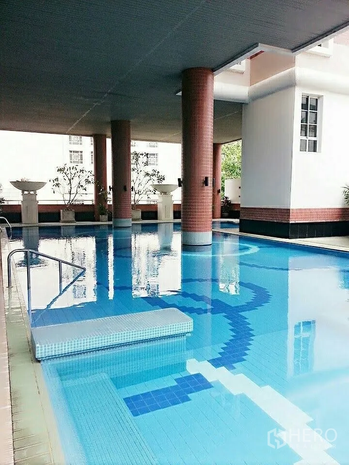 Condominium for rent in Khlong Toei, Bangkok - Covered swimming pool with blue mosaic tiles and supporting columns.