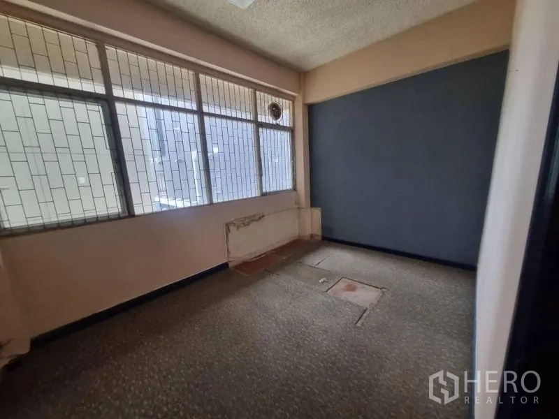 Shophouse for rent in Watthana, Bangkok - Compact office room with grid-style windows and a dark feature wall.