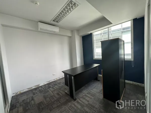 Office Space for rent in Watthana, Bangkok - Private office room with window, air-conditioning and a dark desk, showing light renovation details.